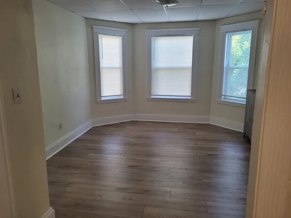 an empty room with wooden floor and windows