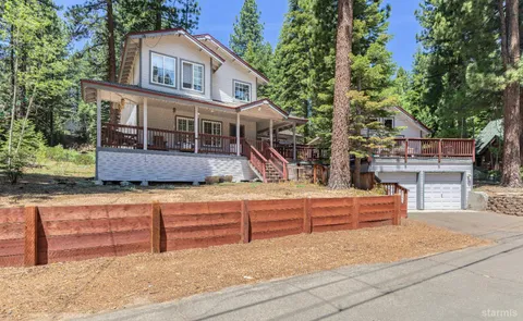 a front view of a house with large trees