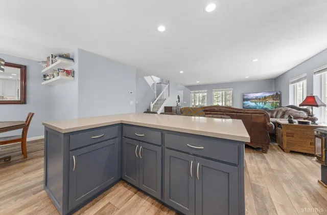 a kitchen with kitchen island granite countertop a sink cabinets and wooden floor