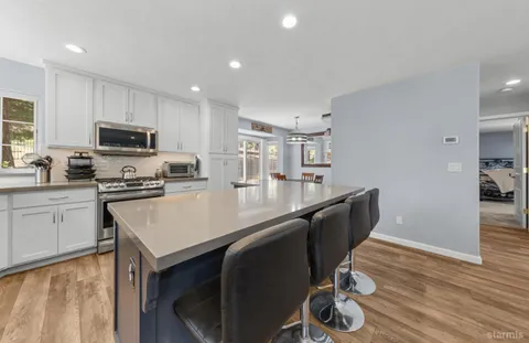 a kitchen with granite countertop a stove a sink a microwave a counter space and cabinets