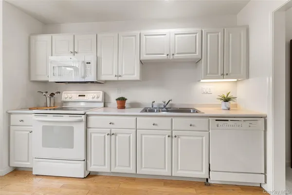 a kitchen with white cabinets and sink