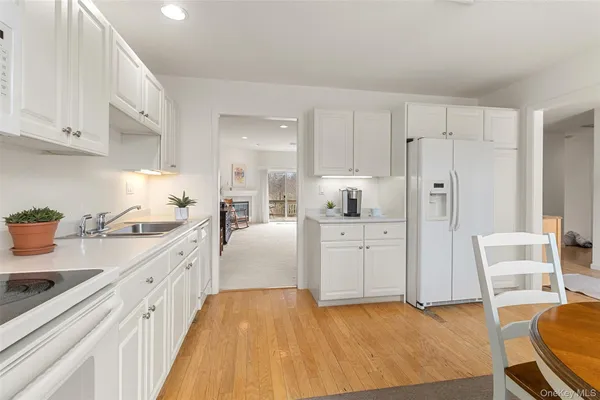 a kitchen with stainless steel appliances granite countertop a stove a sink dishwasher and white cabinets with wooden floor