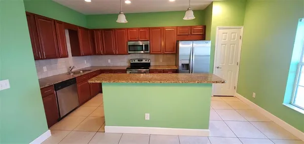 a kitchen with granite countertop a refrigerator a stove top oven and cabinets