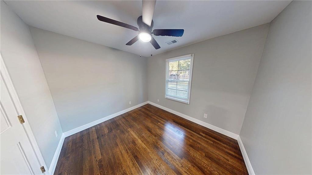 4834 Bartlett Road Forest Park, GA 30297 - Photo 12 of 20 an empty room with wooden floor fan and windows
