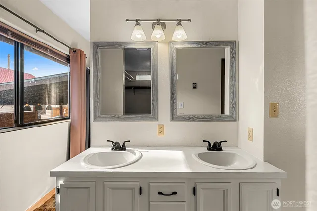 a bathroom with double sink and two mirror