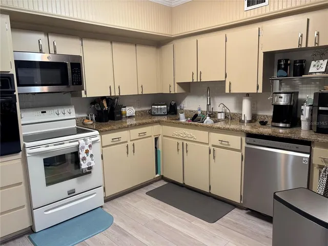 a kitchen with stainless steel appliances granite countertop a stove a sink and a microwave