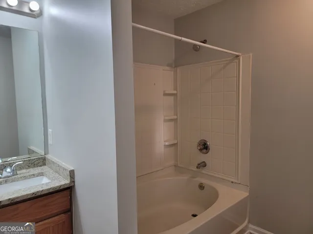 a bathroom with a tub sink vanity and mirror