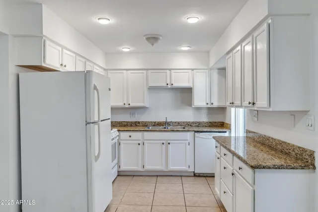 a kitchen with stainless steel appliances granite countertop a refrigerator sink and white cabinets