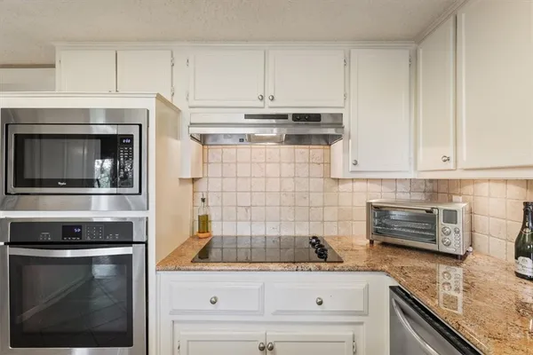 a kitchen with a sink dishwasher a stove a dining table and chairs with wooden floor