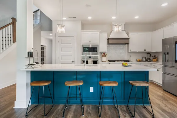 a kitchen with stainless steel appliances granite countertop a table chairs sink and cabinets