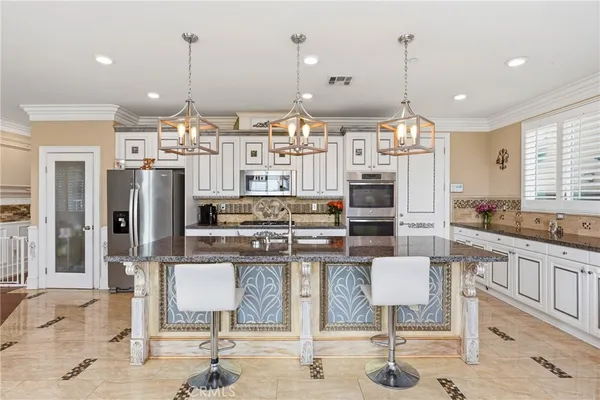 a kitchen with stainless steel appliances kitchen island granite countertop a refrigerator and cabinets