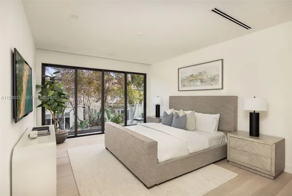 a bedroom with a large bed and a large window with balcony view