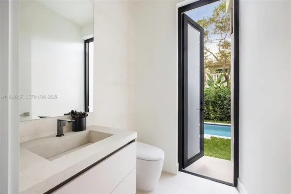 a bathroom with a granite countertop sink a toilet and a window