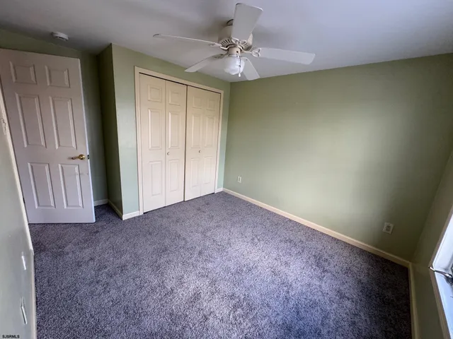 an empty room with a ceiling fan and a window