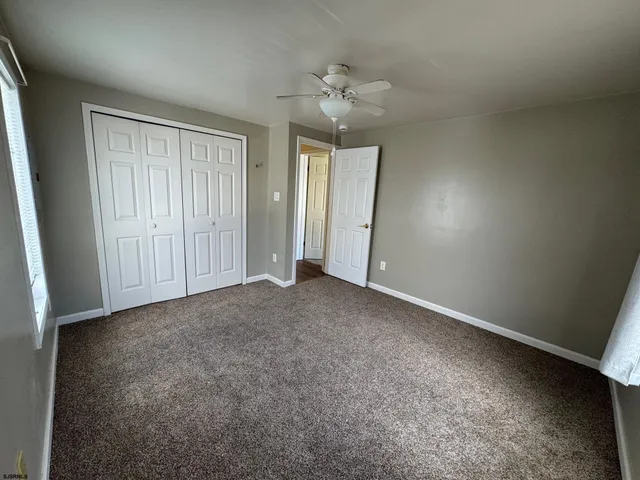 a view of an empty room with a chandelier fan