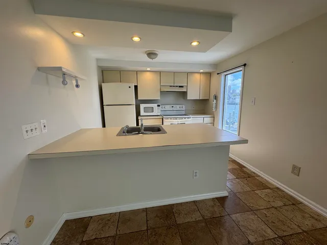a room with kitchen island a sink a stove and a refrigerator