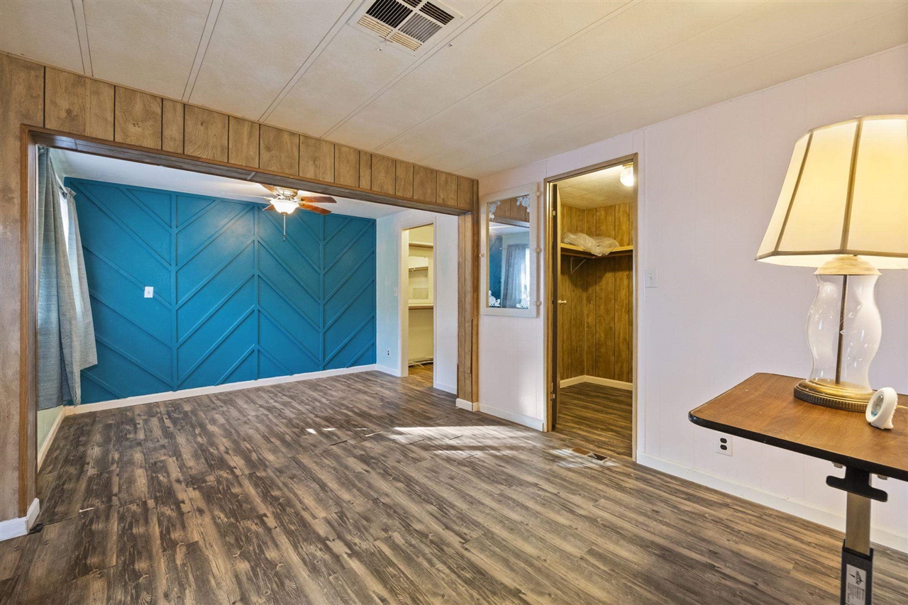 10956 Green Street, Unit 122 Columbia, CA 95310 - Photo 11 of 22 Unfurnished room with a barn door, wooden walls, ceiling fan, and dark wood-type flooring