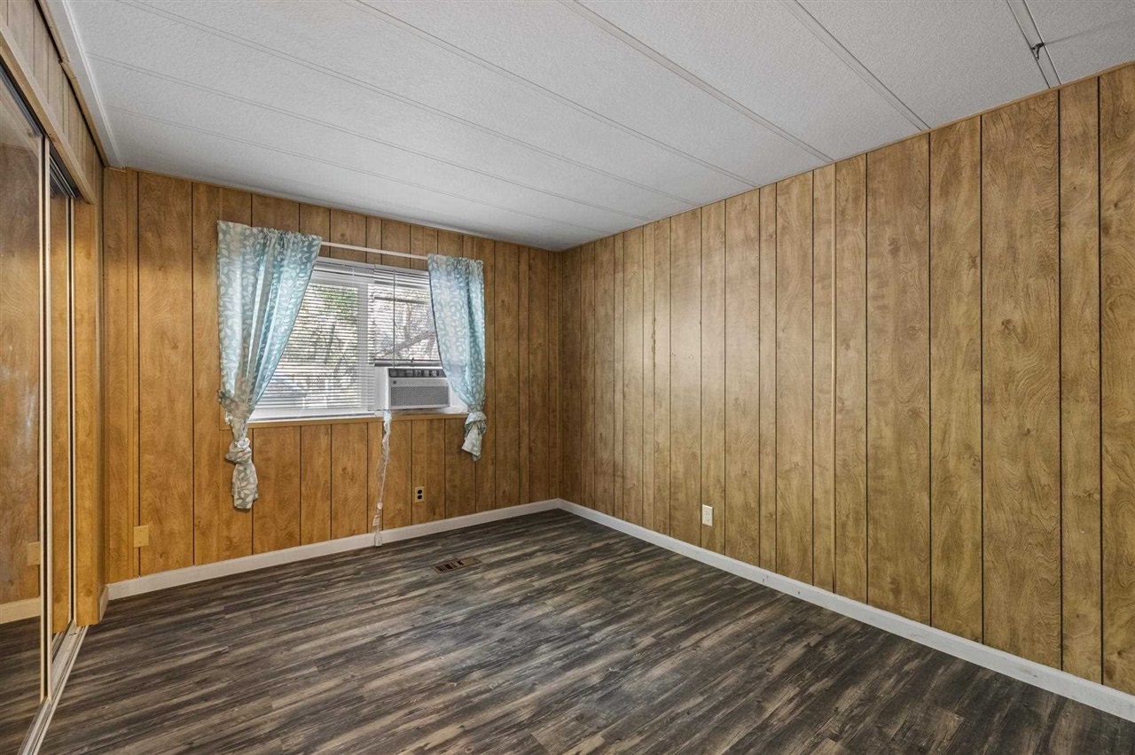 10956 Green Street, Unit 122 Columbia, CA 95310 - Photo 15 of 22 Spare room featuring wood walls, dark hardwood / wood-style floors, a textured ceiling, and cooling unit