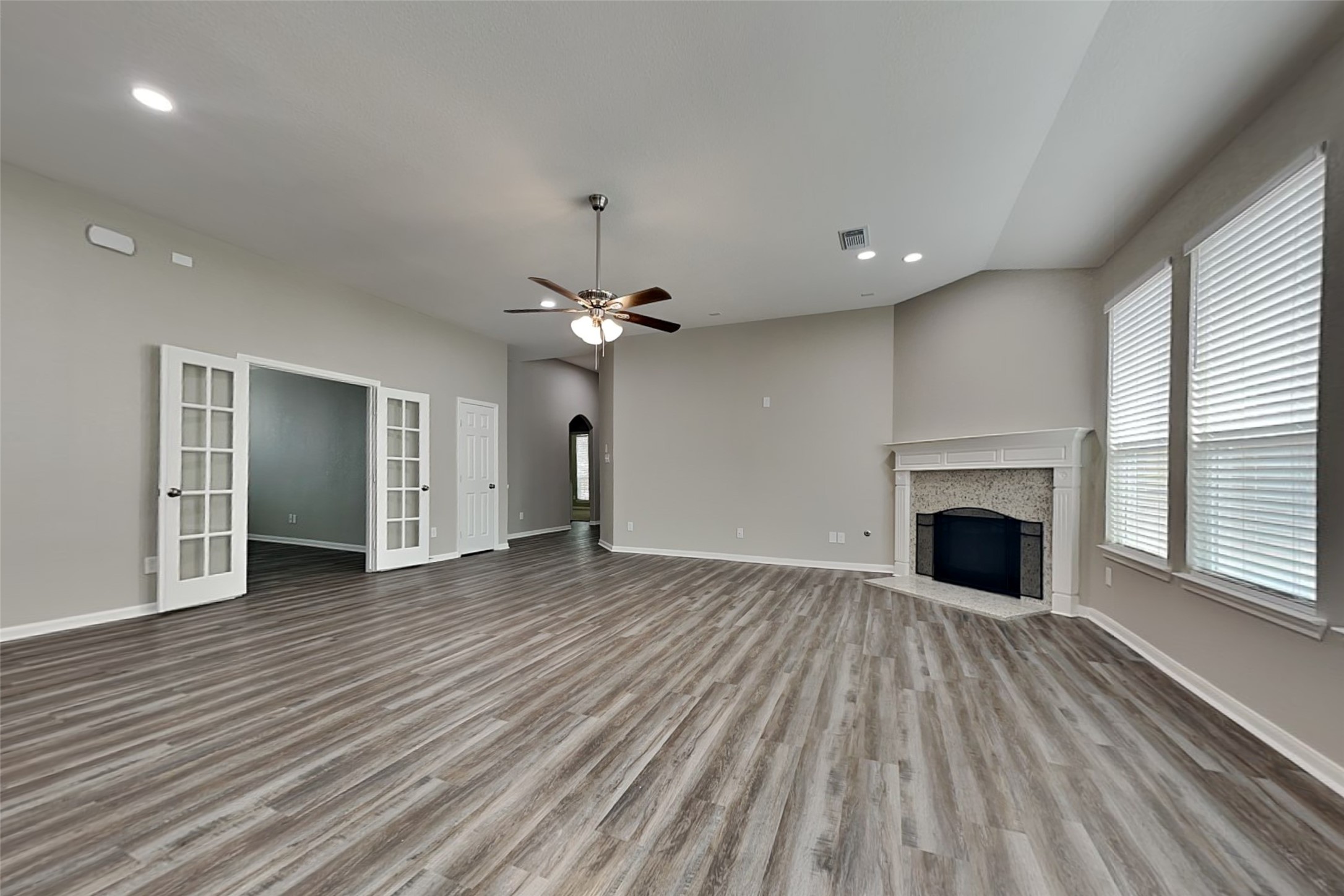 9435 Edgeloch Drive Spring, TX 77379 - Photo 2 of 18 an empty room with wooden floor fireplace cabinet and windows