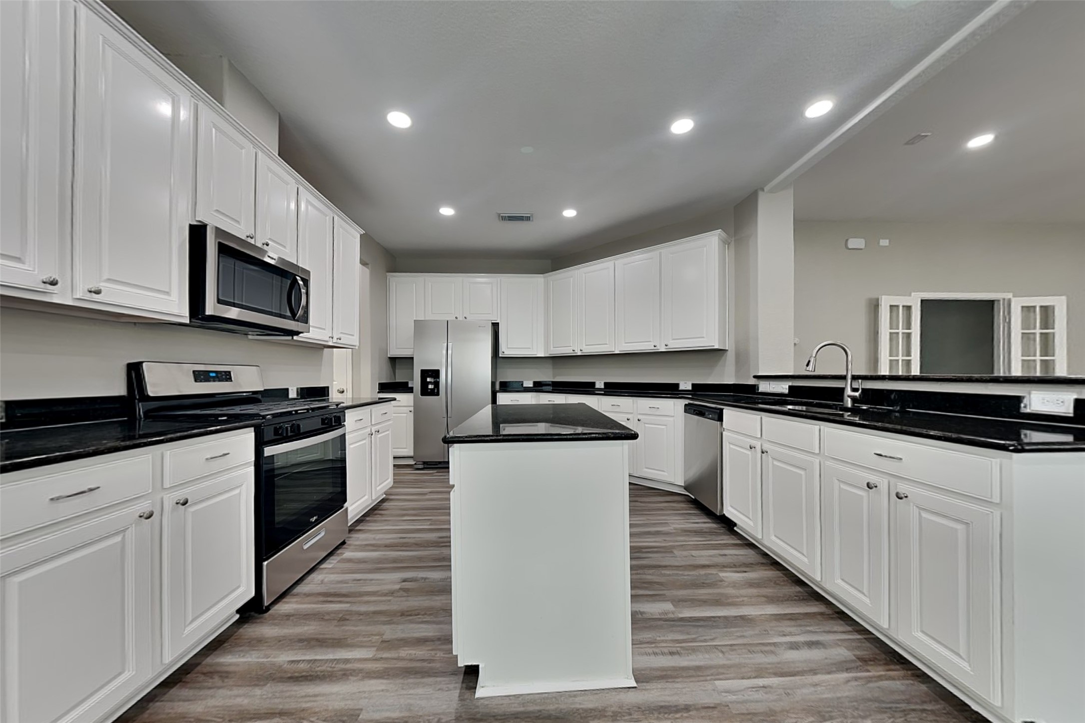 9435 Edgeloch Drive Spring, TX 77379 - Photo 6 of 18 a kitchen with stainless steel appliances granite countertop a stove top oven a sink dishwasher and a microwave oven with wooden floor