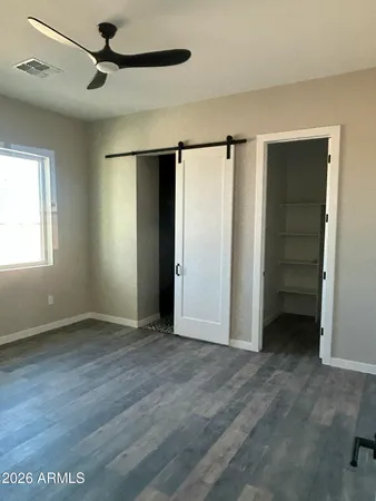 an empty room with closet and a ceiling fan