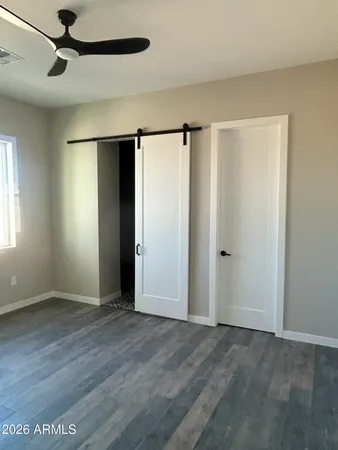 an empty room with wooden floor closet and windows