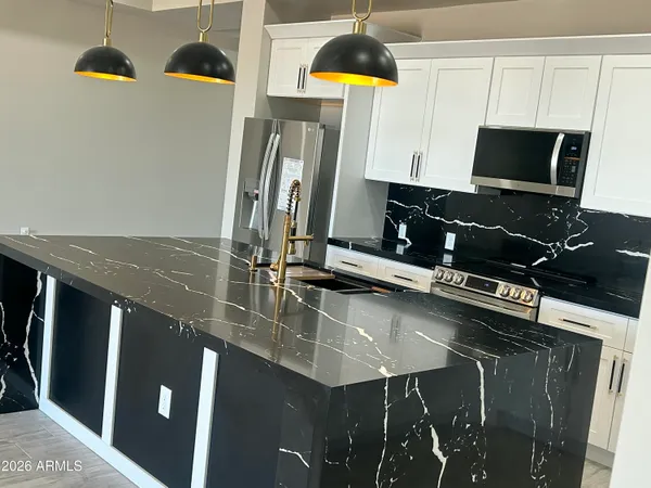 a view of kitchen with stainless steel appliances granite countertop a refrigerator a sink a stove and a wooden floors