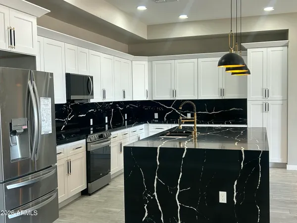 a kitchen with stainless steel appliances granite countertop a stove a sink and a refrigerator