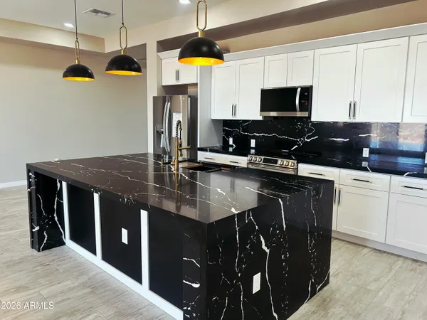 a kitchen with kitchen island granite countertop a sink appliances and cabinets