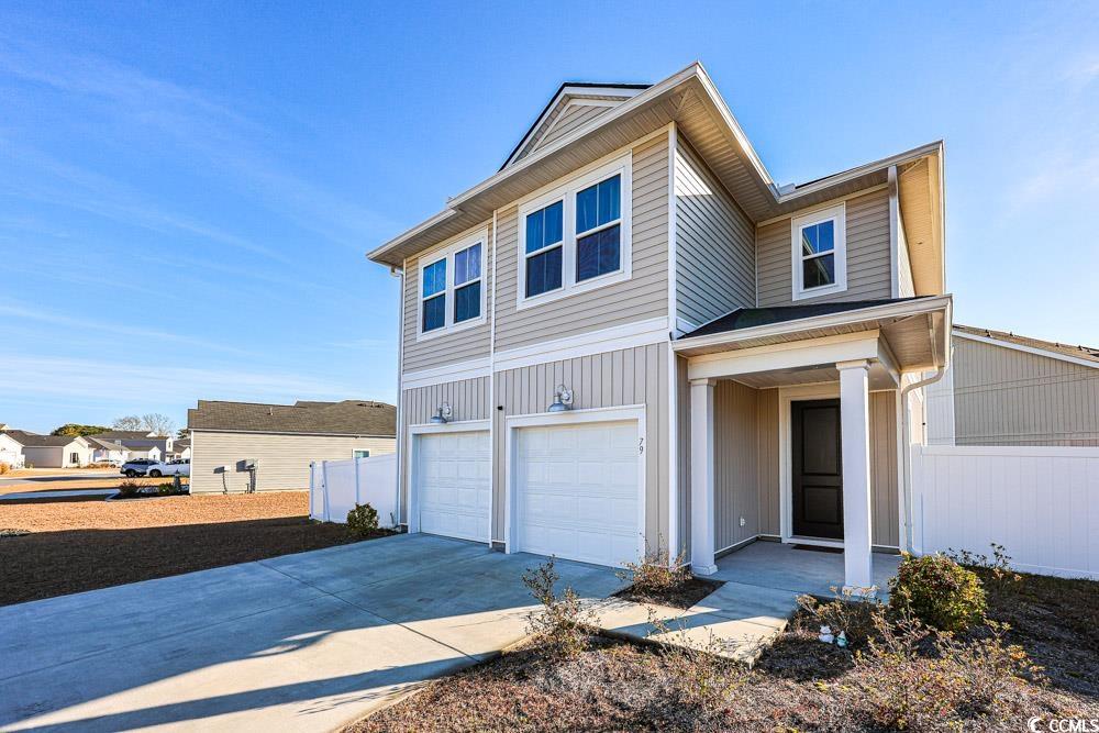 Traditional-style house with an attached garage, concrete driveway, and board and batten siding