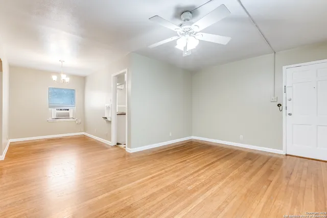 an empty room with wooden floor and ceiling fan
