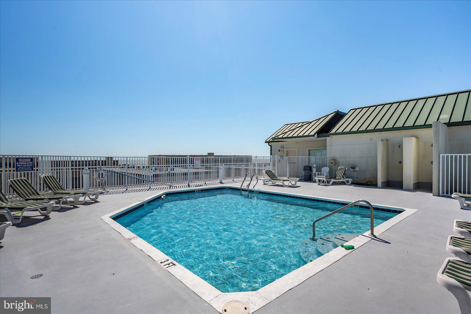 5300 Coastal Highway, Unit 101 Ocean City, MD 21842 - Photo 47 of 85 a view of a swimming pool with lawn chairs potted plants with sky view