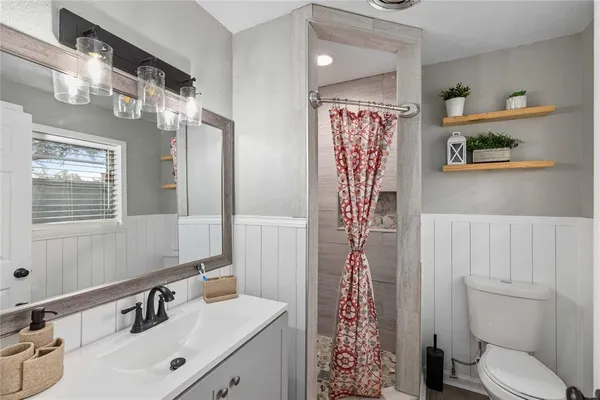 a bathroom with a sink a toilet and shower curtain