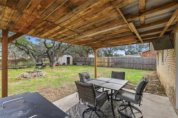 a view of a backyard with table and chairs with wooden floor and fence