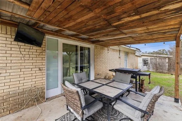 a patio with table and chairs and potted plants