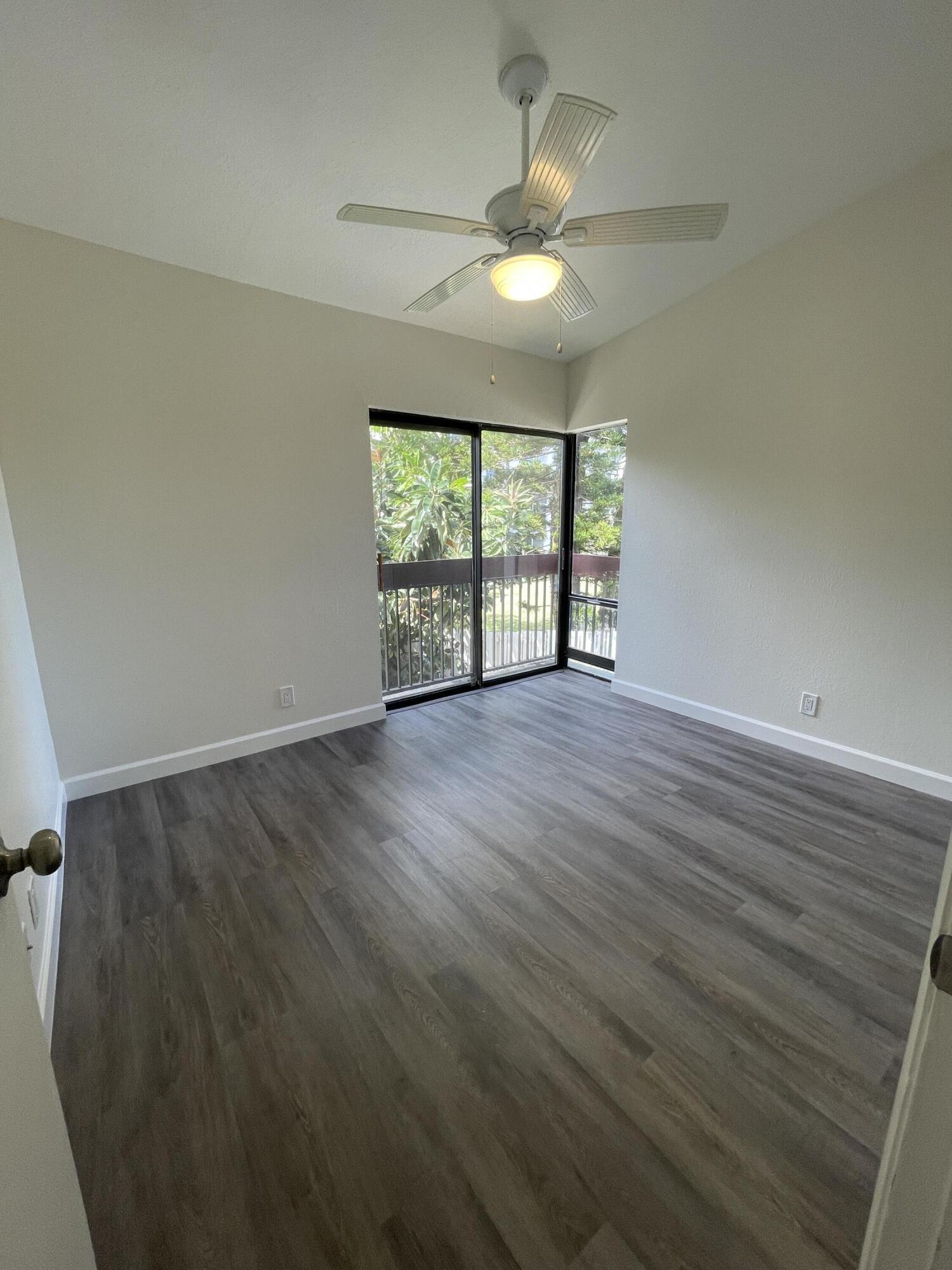 2297 Southwest 15th Street, Unit 122 Deerfield Beach, FL 33442 - Photo 15 of 47 an empty room with wooden floor chandelier fan and windows
