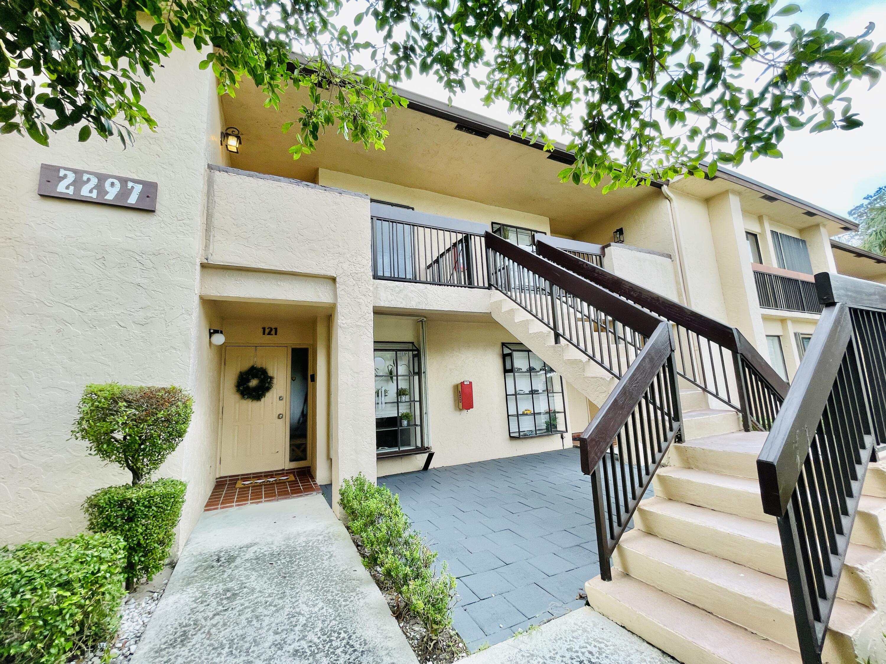 2297 Southwest 15th Street, Unit 122 Deerfield Beach, FL 33442 - Photo 2 of 47 a view of a house with a small yard plants and large tree