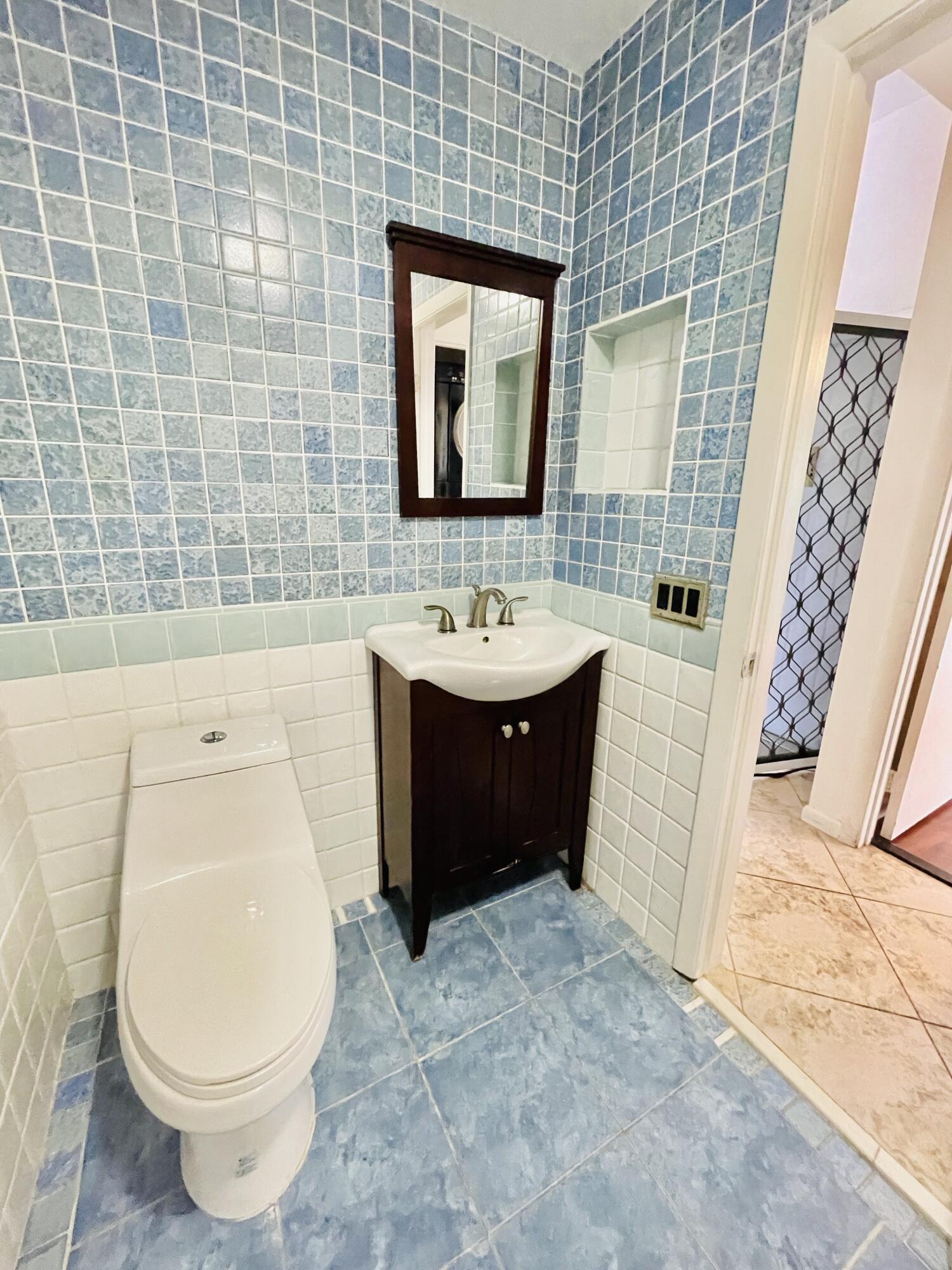 2297 Southwest 15th Street, Unit 122 Deerfield Beach, FL 33442 - Photo 22 of 47 a bathroom with a toilet sink and mirror