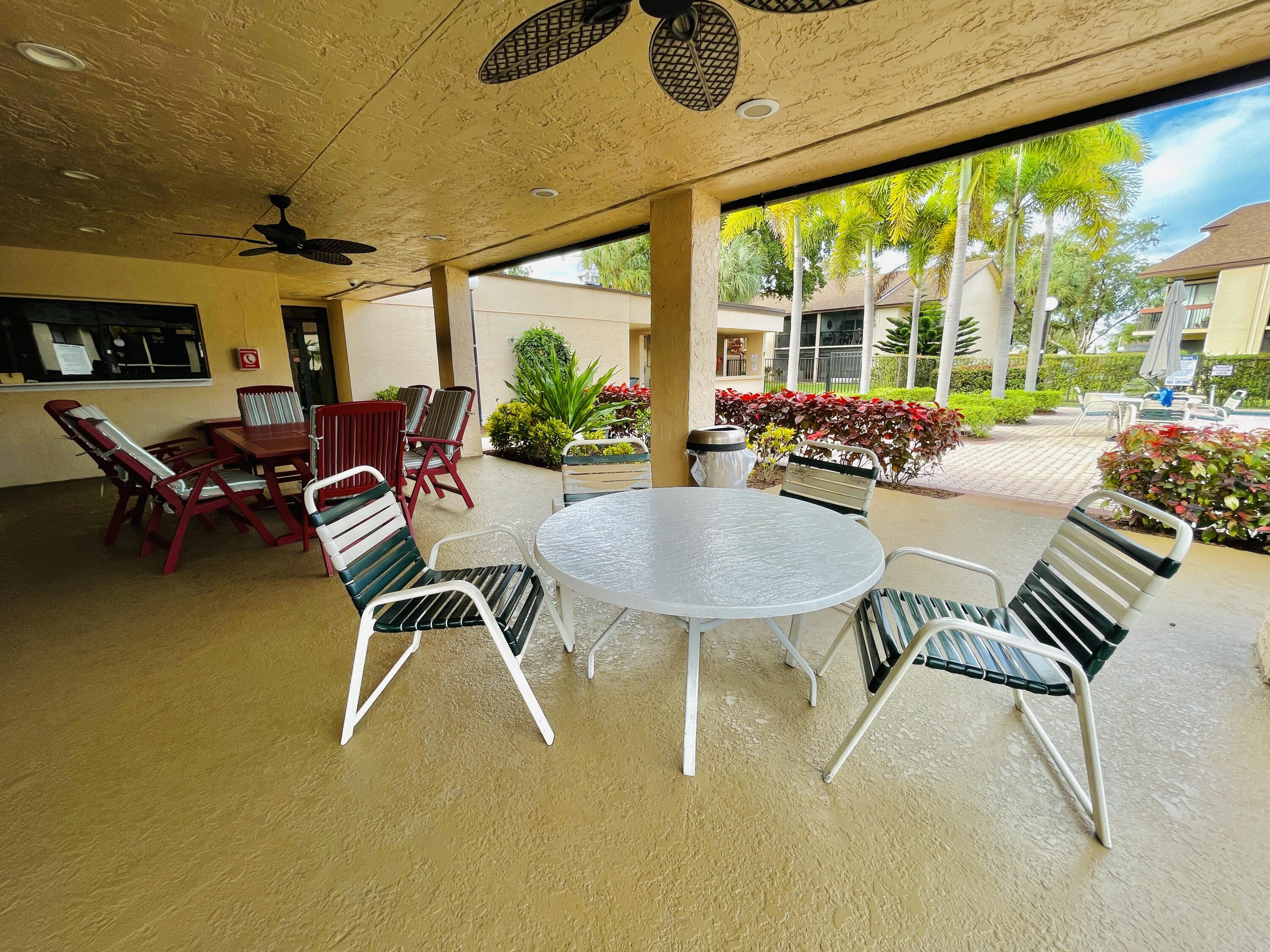 2297 Southwest 15th Street, Unit 122 Deerfield Beach, FL 33442 - Photo 35 of 47 a view of a patio with table and chairs next to a yard