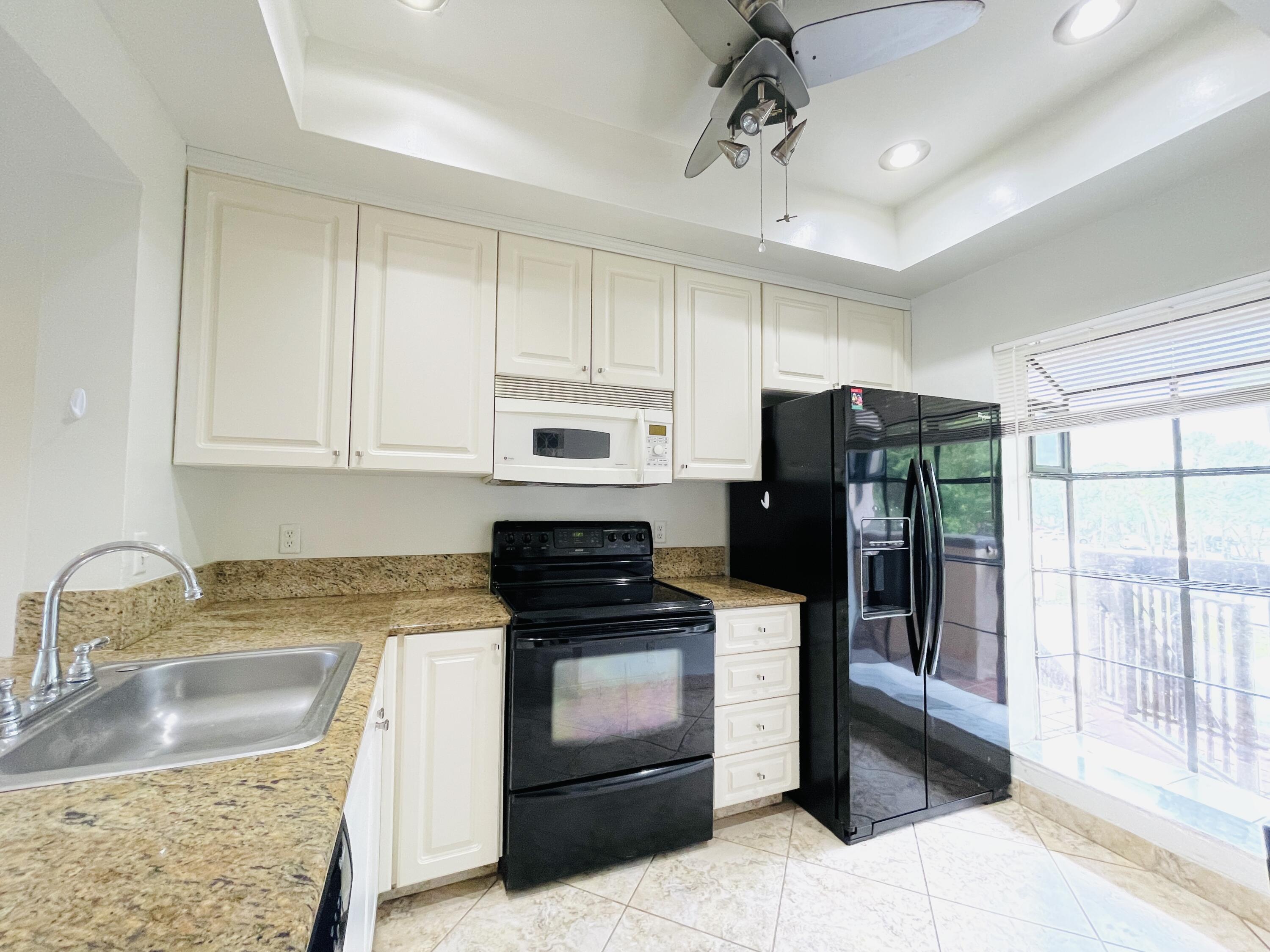 2297 Southwest 15th Street, Unit 122 Deerfield Beach, FL 33442 - Photo 7 of 47 a kitchen with granite countertop a refrigerator stove and sink
