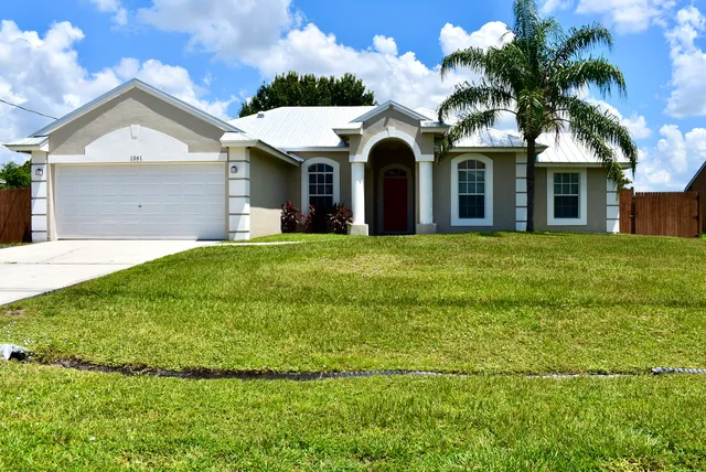 a view of a white house with a big yard and palm trees