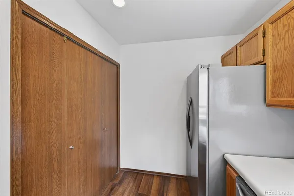 a view of a refrigerator in kitchen and an empty room