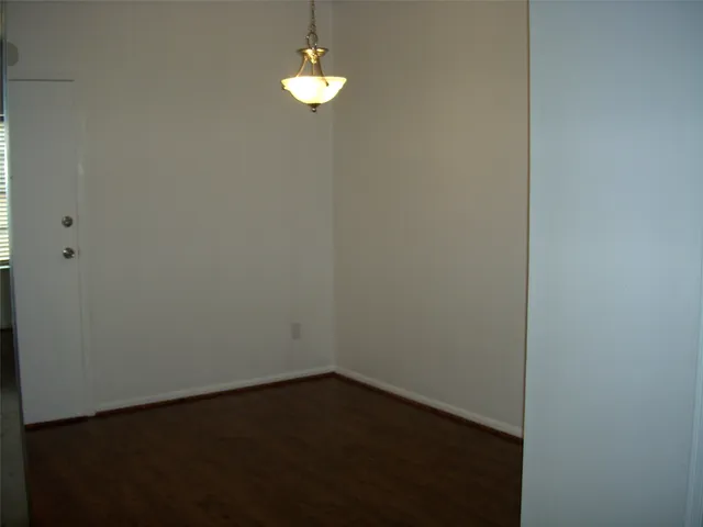 a view of empty room with wooden floor and chandelier