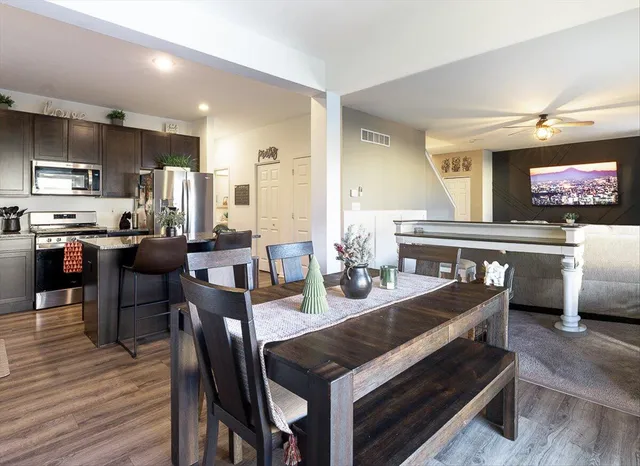 a kitchen with granite countertop stainless steel appliances a table chairs refrigerator and microwave