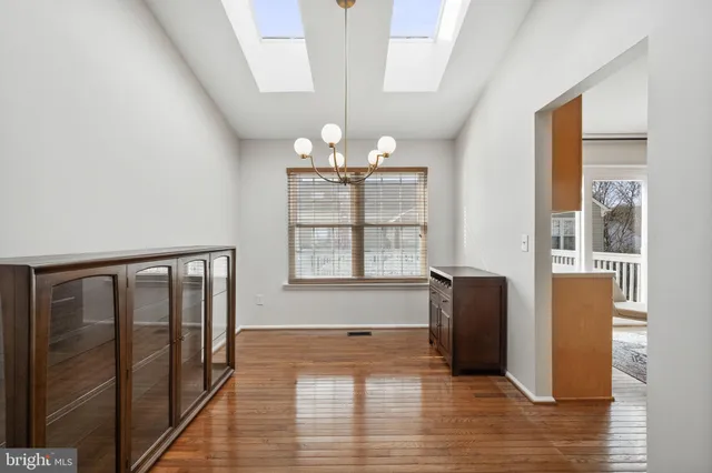 an empty room with wooden floor mirror and windows