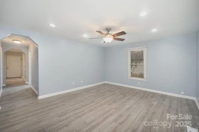 an empty room with wooden floor and a ceiling fan