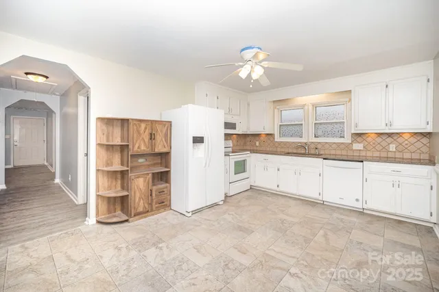 a large white kitchen with a refrigerator a stove a microwave and cabinets
