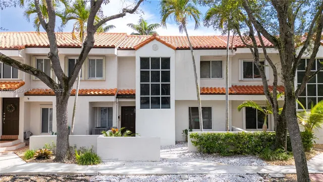 a front view of a building with garden and parking
