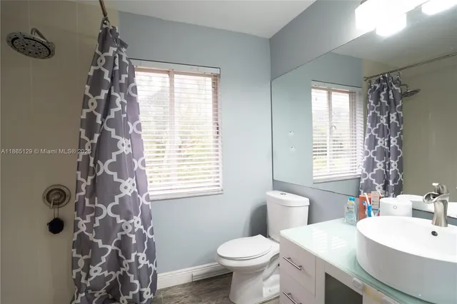 a bathroom with a sink toilet a mirror and shower