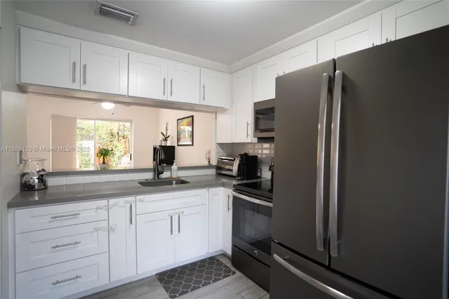 a kitchen with a refrigerator and white cabinets